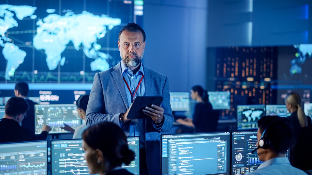 Diverse Team in a Modern Control Center Analyzes Global Data on Multiple Screens