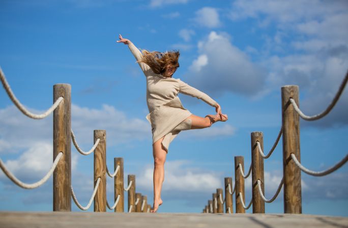 Young woman jumping and posing on footbridge
