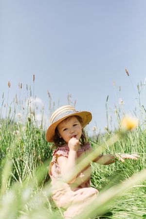 Cute little girl sitting in grassy meadow