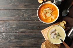 Two bowls of soup on wooden table with copy space