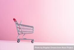 Tiny shopping cart on pink background beqBlb