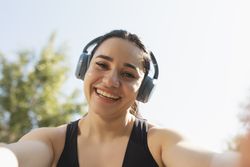 A young woman takes a selfie while listening music and practice sports in a park in the morning, Zaragoza, Spain