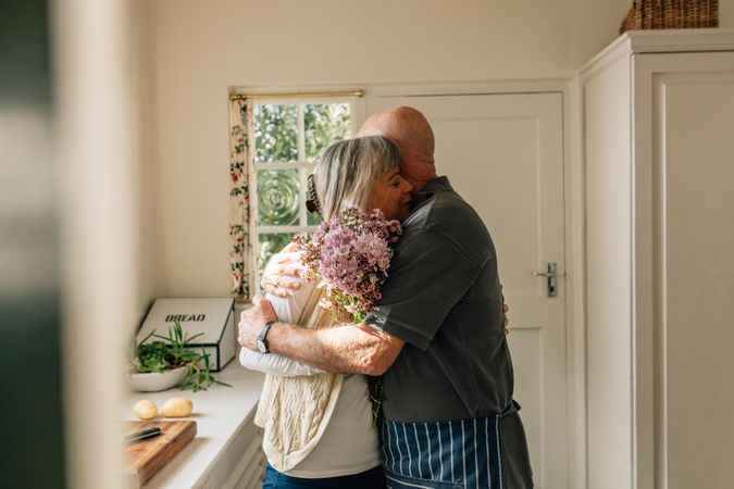 Older man hugging his wife standing in kitchen
