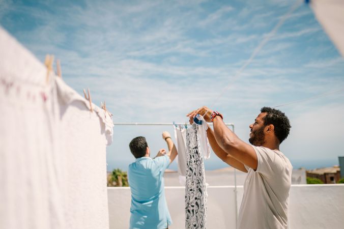 Multiracial men hanging clothes in bright day