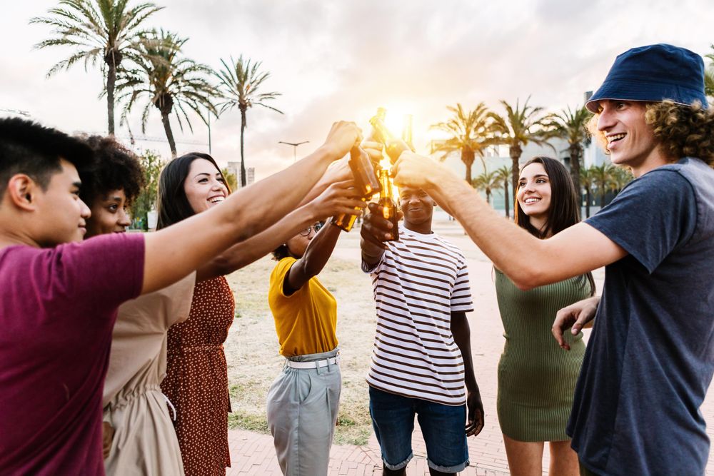 Group of happy young multiracial friends with drinks celebrating in summer party