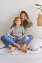 Mother hugging curly haired son with crossed legs
