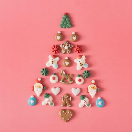 Festive tree made out of holiday cookies on salmon background