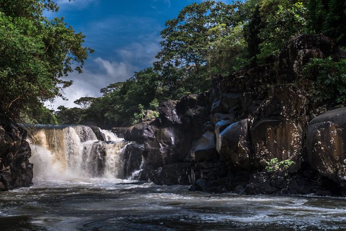 Rocky waterfall under blue sky with clouds