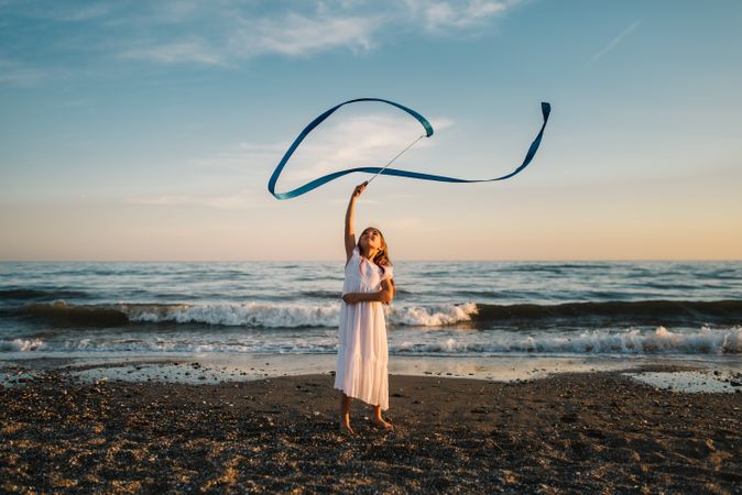 Adorable girl playing with ribbon on seaside