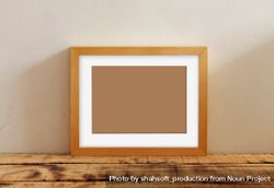 Rectangular picture frame with brown interior mockup on wooden desk 47GgB4
