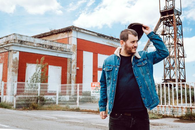 Man taking off cap outside industrial building