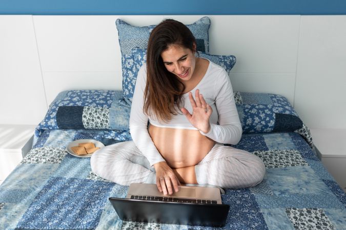 Pregnant woman talking on video chat on laptop