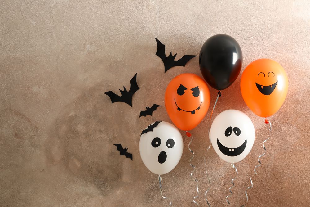 Different balloons on brown background. Halloween concept, space for text