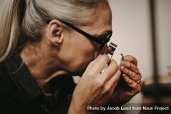 Close up of woman jeweler examining diamond through loupe at workshop 4A3Lz0