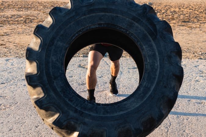 Anonymous strong man doing tire flip exercise