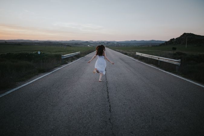 Anonymous woman running along countryside road