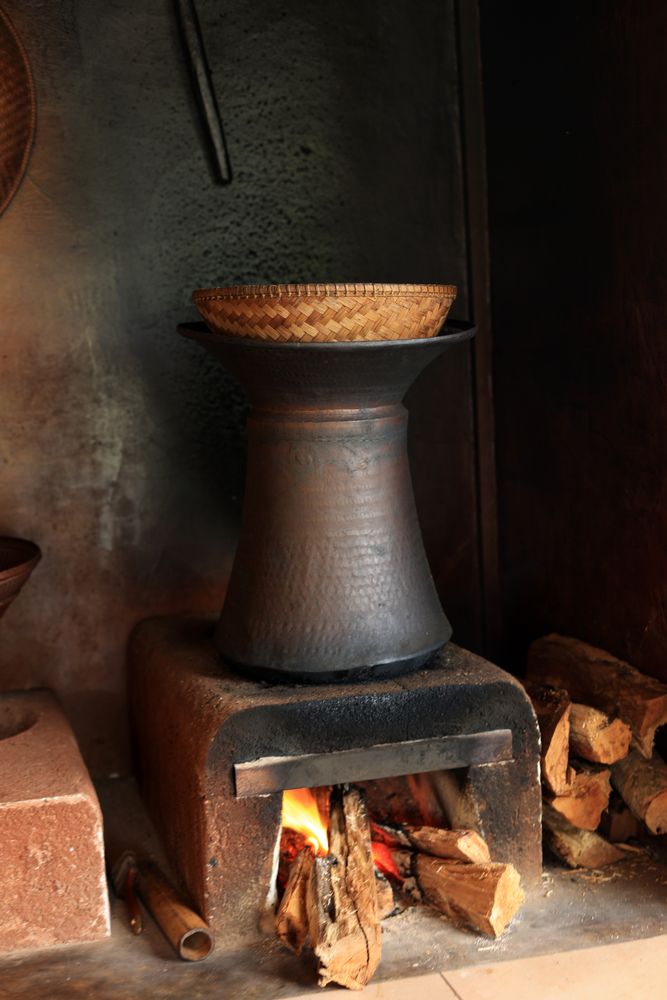 Indonesian traditional kitchen steaming rice using bamboo and earthenware cooking pot on wooden fireplace