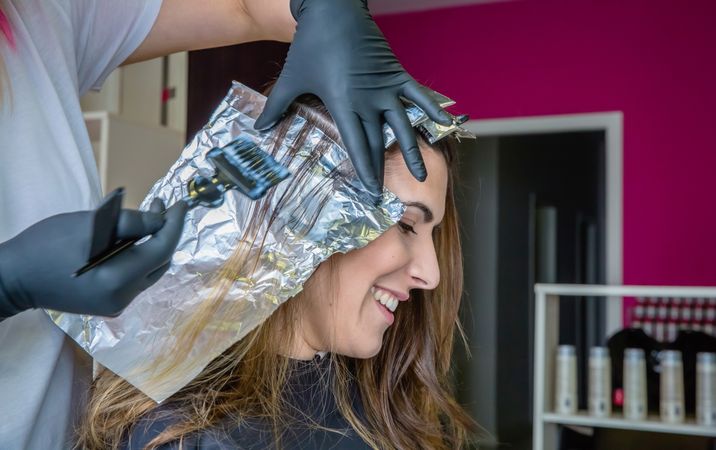 Woman smiling while having highlights put in hair