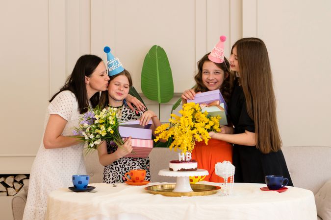 Family gathered around birthday cake with colorful hats