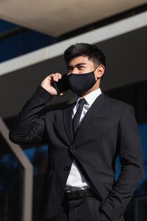 Serious male entrepreneur talking on smartphone in city