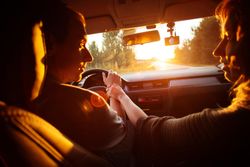 Inside of vehicle with man driving and girlfriend holding his hand