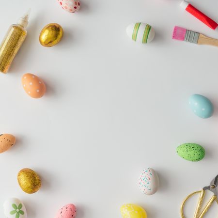 Pastel Easter eggs on light background with crafting tools