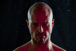 Serious bald man under rain and red light