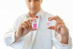 Man in white lab coat studying sample