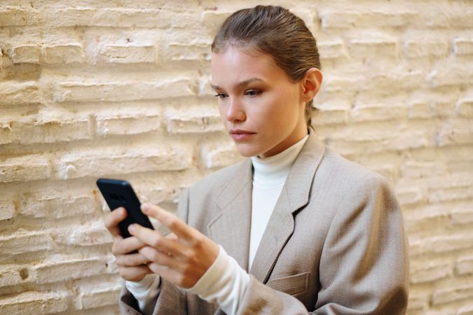 A focused young woman is fully engaged with her smartphone while in a modern and vibrant setting