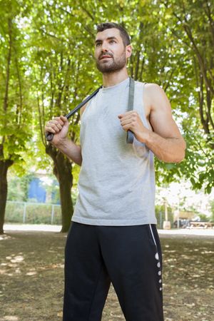 Sportsman stretching and resting with rubber in park