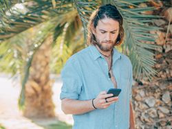Young hipster man texting in jungle