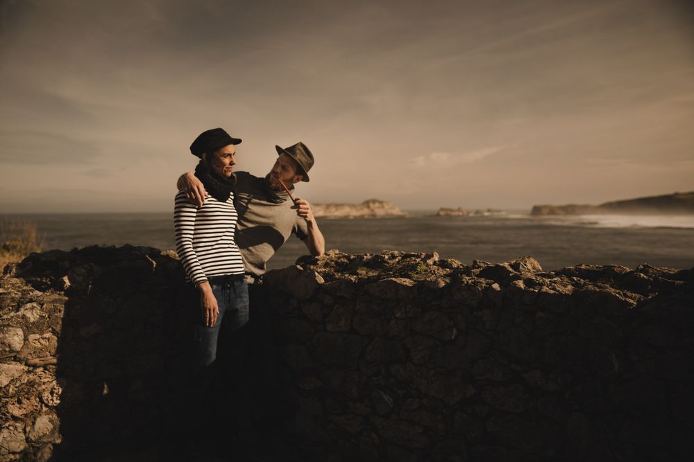 Man holding woman on hands near stones on shore