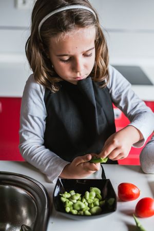 Young girl preparing vegetables for salad