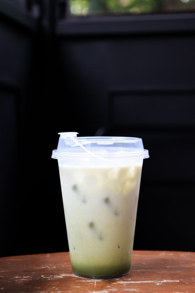 Iced Matcha Latte Green Tea with Milk Foam in a Plastic Takeaway Glass