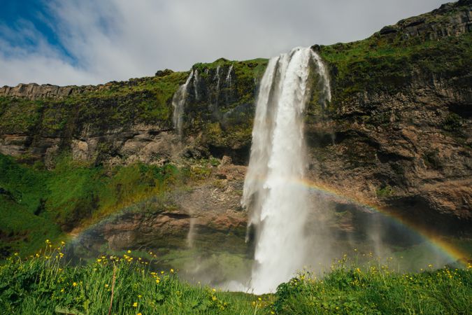 Amazing waterfall from cliff and rainbow on lawn