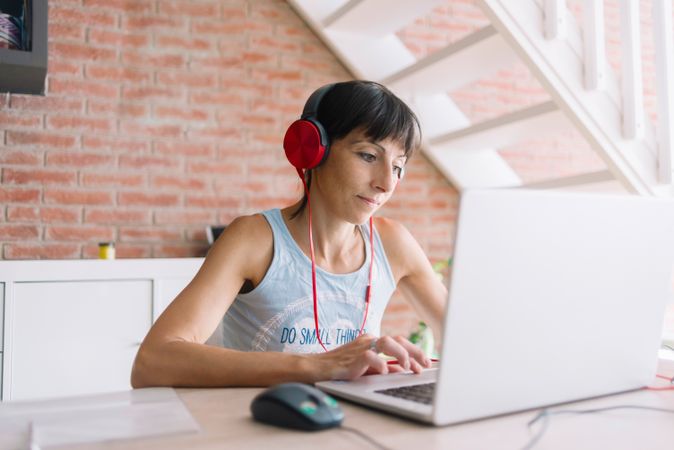 Woman in headphones working at laptop at home