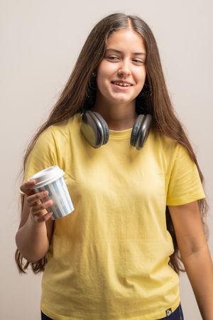 A young female student holding a paper cup of coffee, on a break.