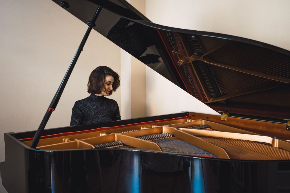 Young woman playing notes behind a piano