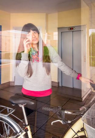 Woman with fixie bike leaving hall behind a glass