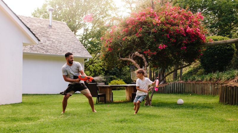 Man playing with little boy in backyard lawn
