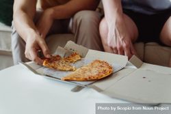 Cropped image of two people eating pizza in living room 0yMaG0