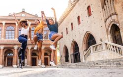 Three happy women dancing in Italian square