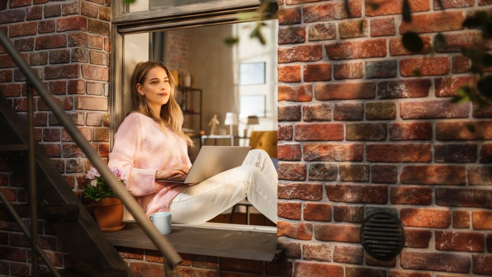 Portrait of Young Woman Using Laptop at home During Warm Afternoon.
