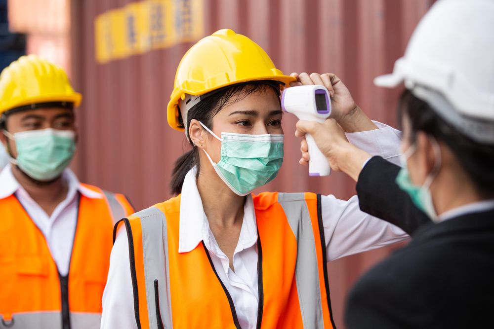 Female worker having temperature taken on construction site