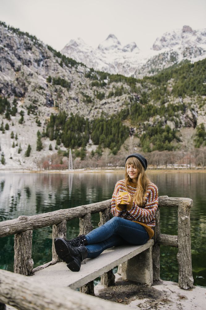 Woman on seat near wonderful lake between hills in snow