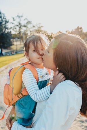Mother kissing daughter in park