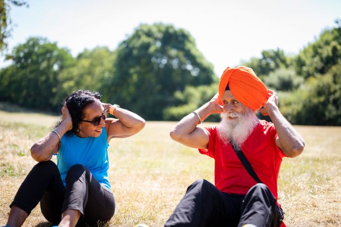 Mature Sikh couple doing sit ups in field
