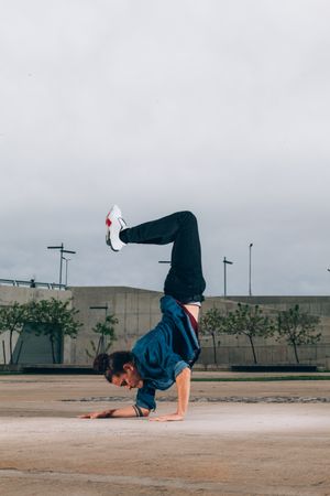 Skillful break dancer performing handstand while moving
