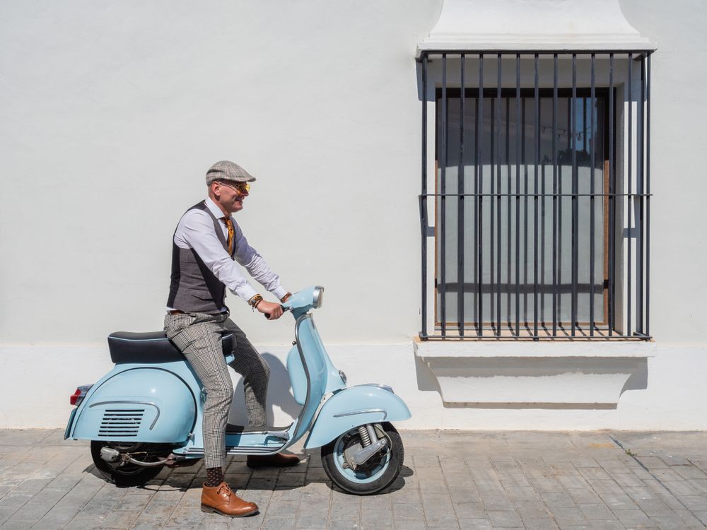 Trendy man sitting on vintage scooter