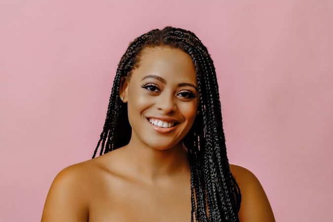 Studio portrait of smiling female with braided hair in pink room